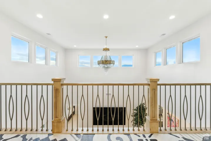 Hall featuring recessed lighting, healthy amount of natural light, and a chandelier with Juliet style inner balcony and with large glass sliding doors.