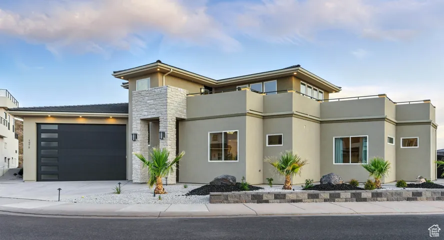 View of front of house with stucco siding, stone siding, a garage, and driveway