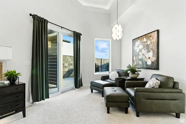 Sitting room with light colored carpet and a chandelier located in the primary bathroom. The slider leads to an outdoor shower and patio off of the back yard pool patio.
