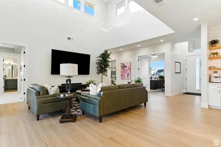 Living room featuring light wood-style flooring, recessed lighting, and a towering ceiling