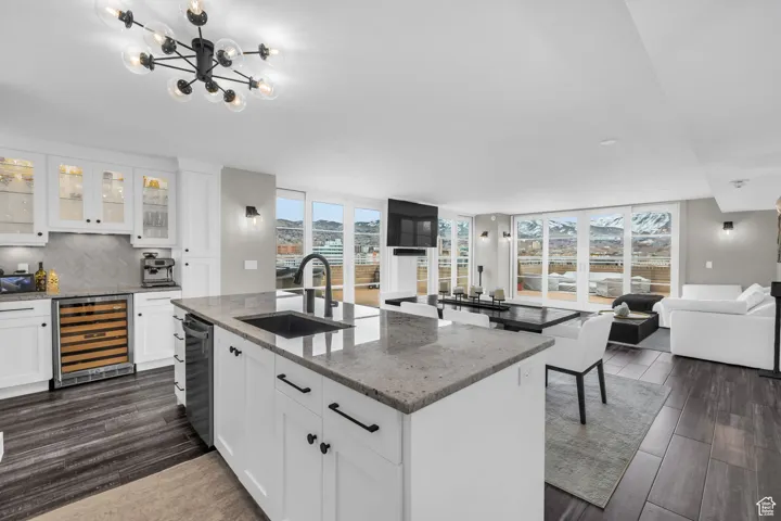 Kitchen featuring open floor plan, glass insert cabinets, white cabinetry, light stone countertops, and a wall of windows