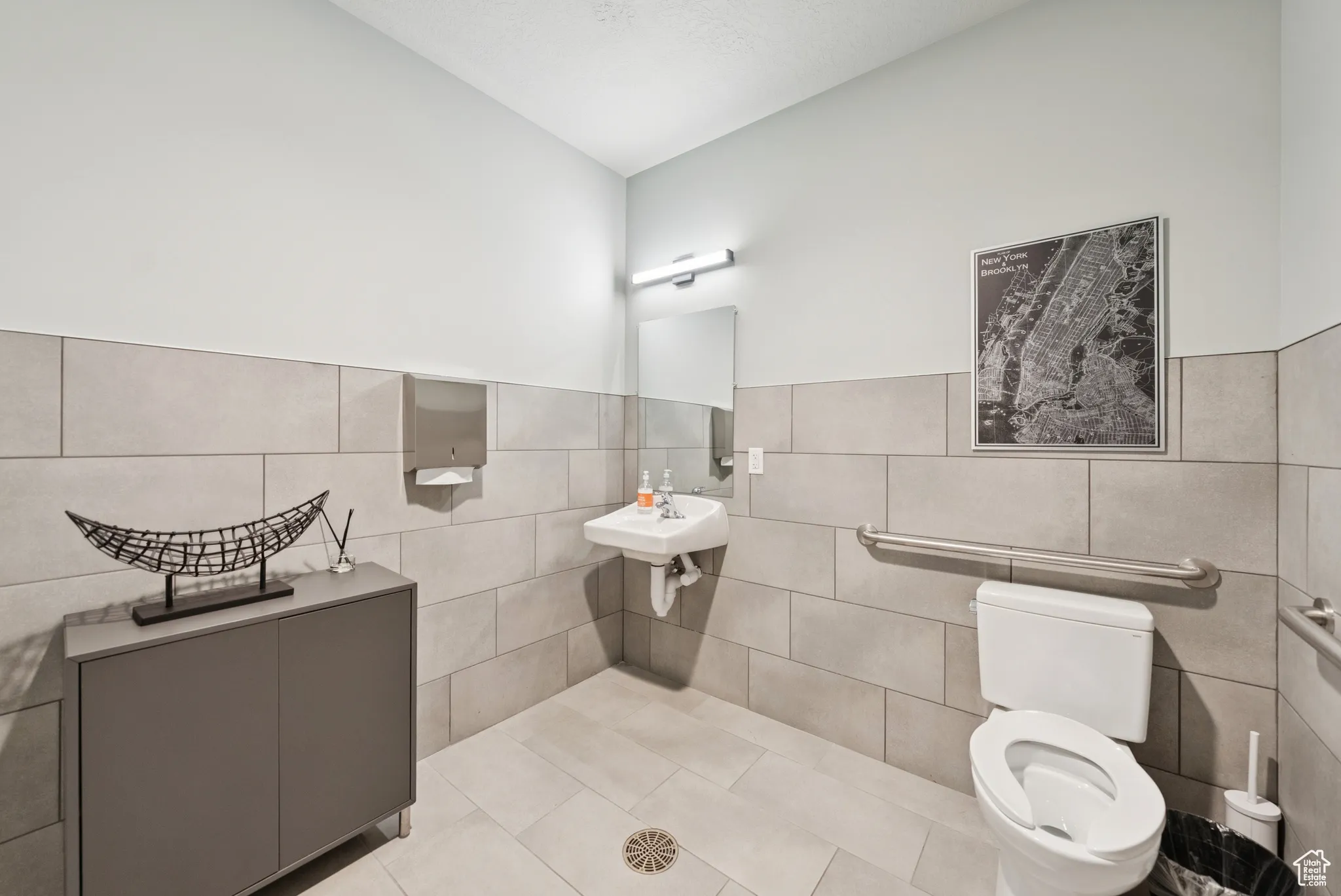 Bathroom with tile walls, tile patterned flooring, and a wainscoted wall