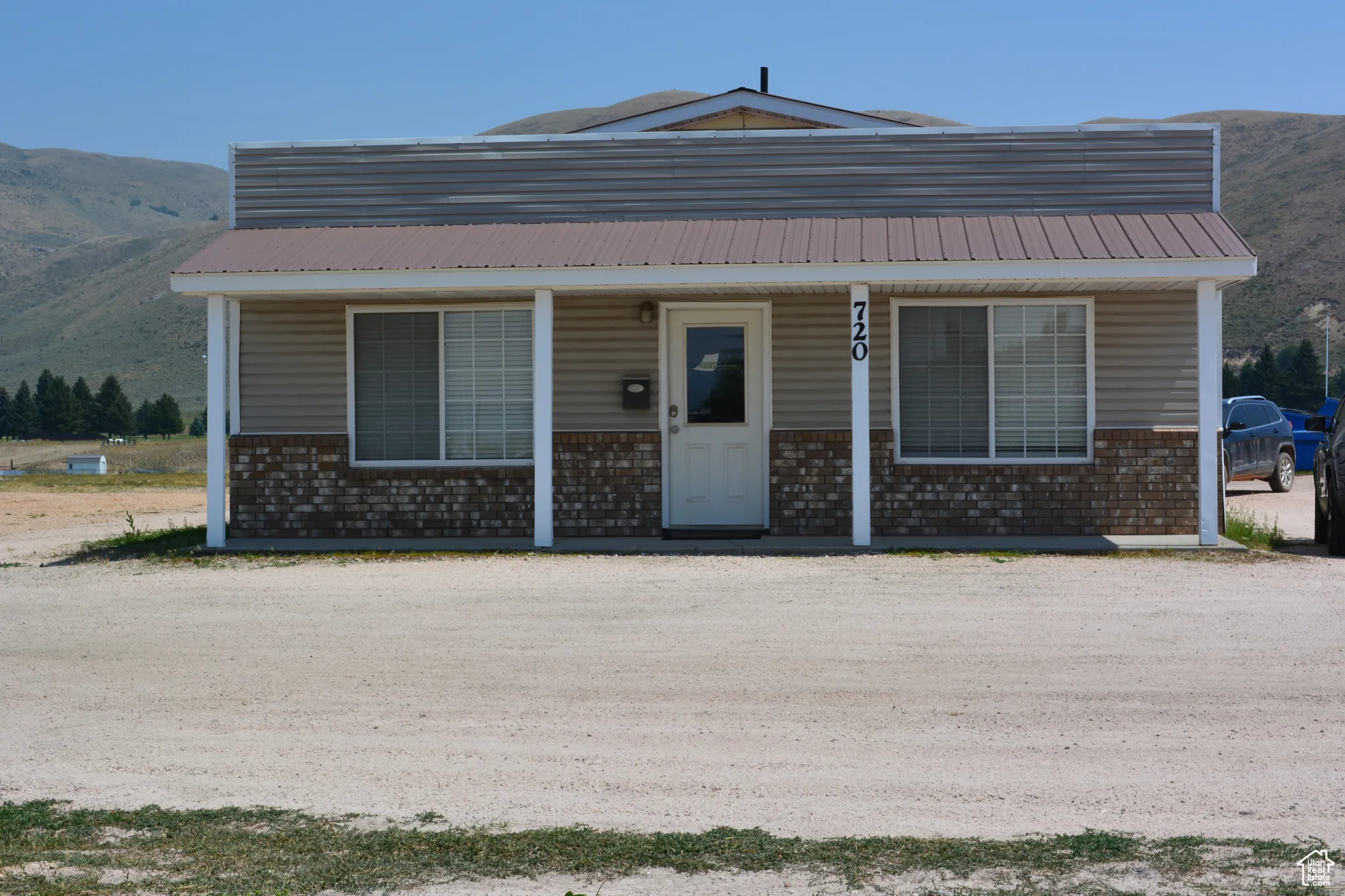View of front of property featuring a mountain view, brick siding, a porch, and a metal roof