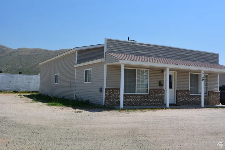 View of front of home featuring brick siding, a metal roof, a porch, and a mountain view