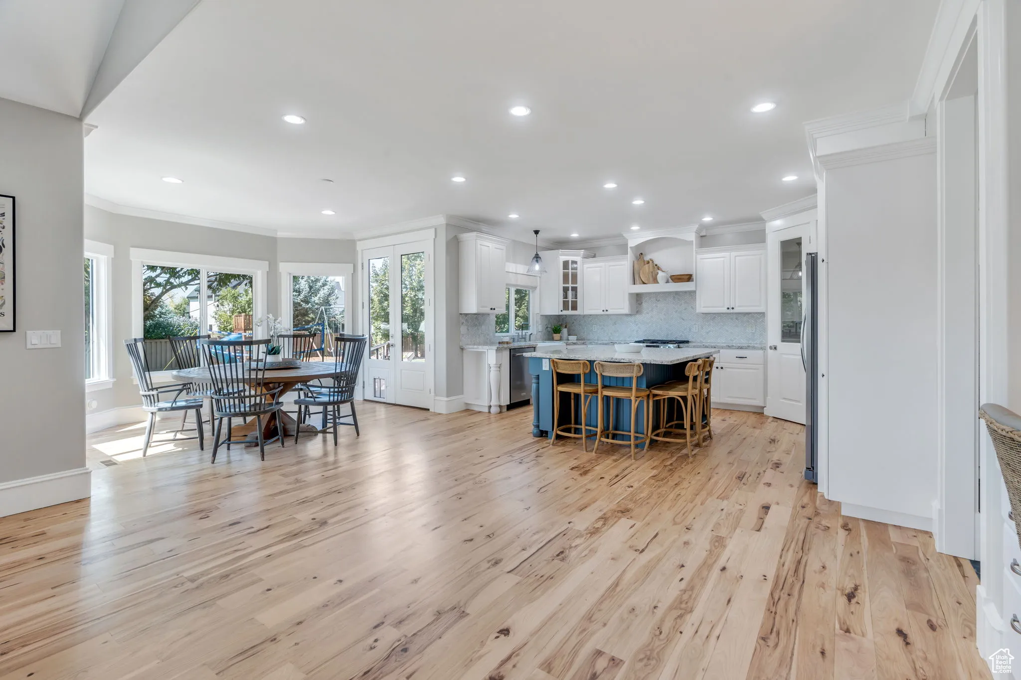 Kitchen with white cabinets, backsplash, ornamental molding, glass insert cabinets, and light wood-type flooring
