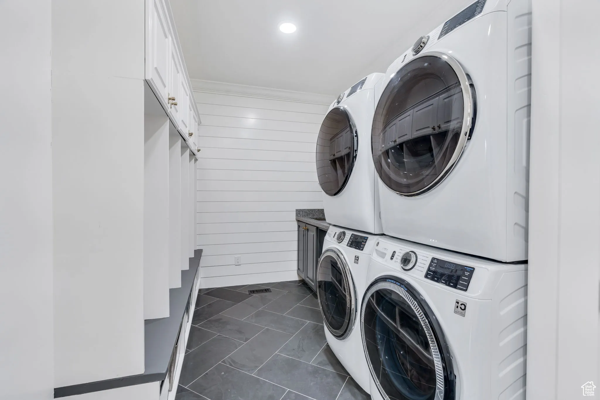 Laundry room featuring cabinet space, wooden walls, ornamental molding, and recessed lighting