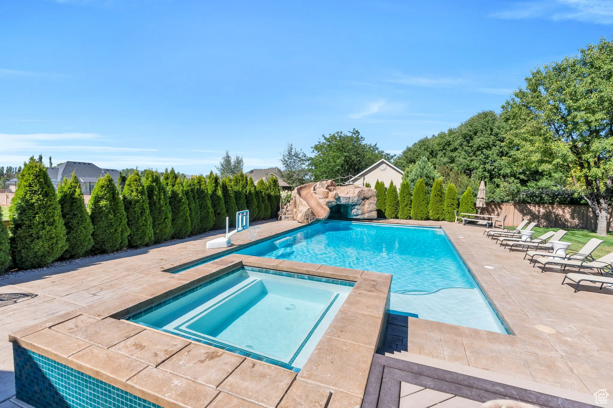 View of pool featuring a patio, an in-ground hot tub, and a water slide