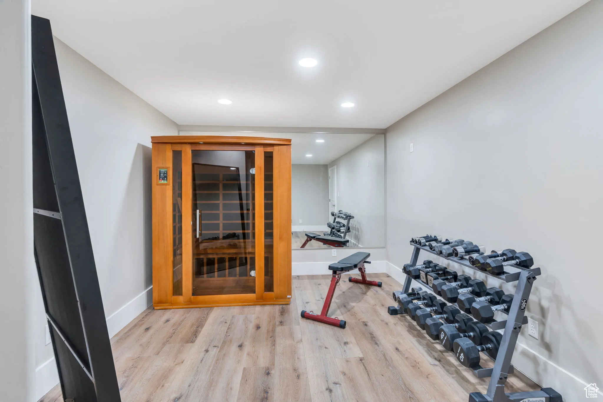 Workout room featuring a sauna, light wood finished floors, and recessed lighting