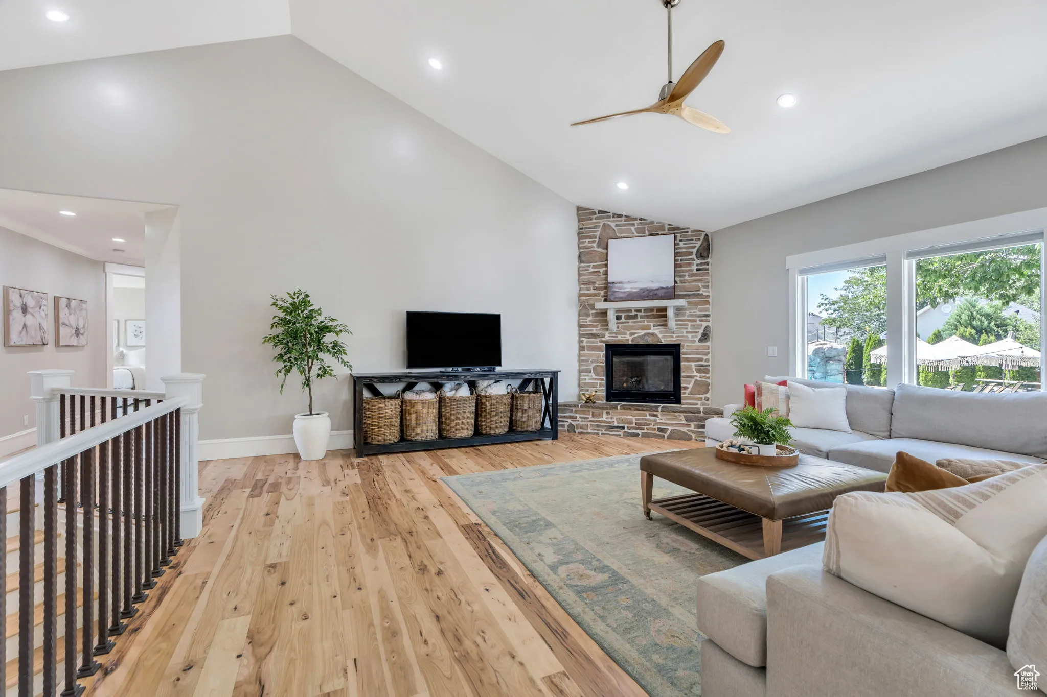 Living area featuring high vaulted ceiling, recessed lighting, a fireplace, light wood-type flooring, and ceiling fan