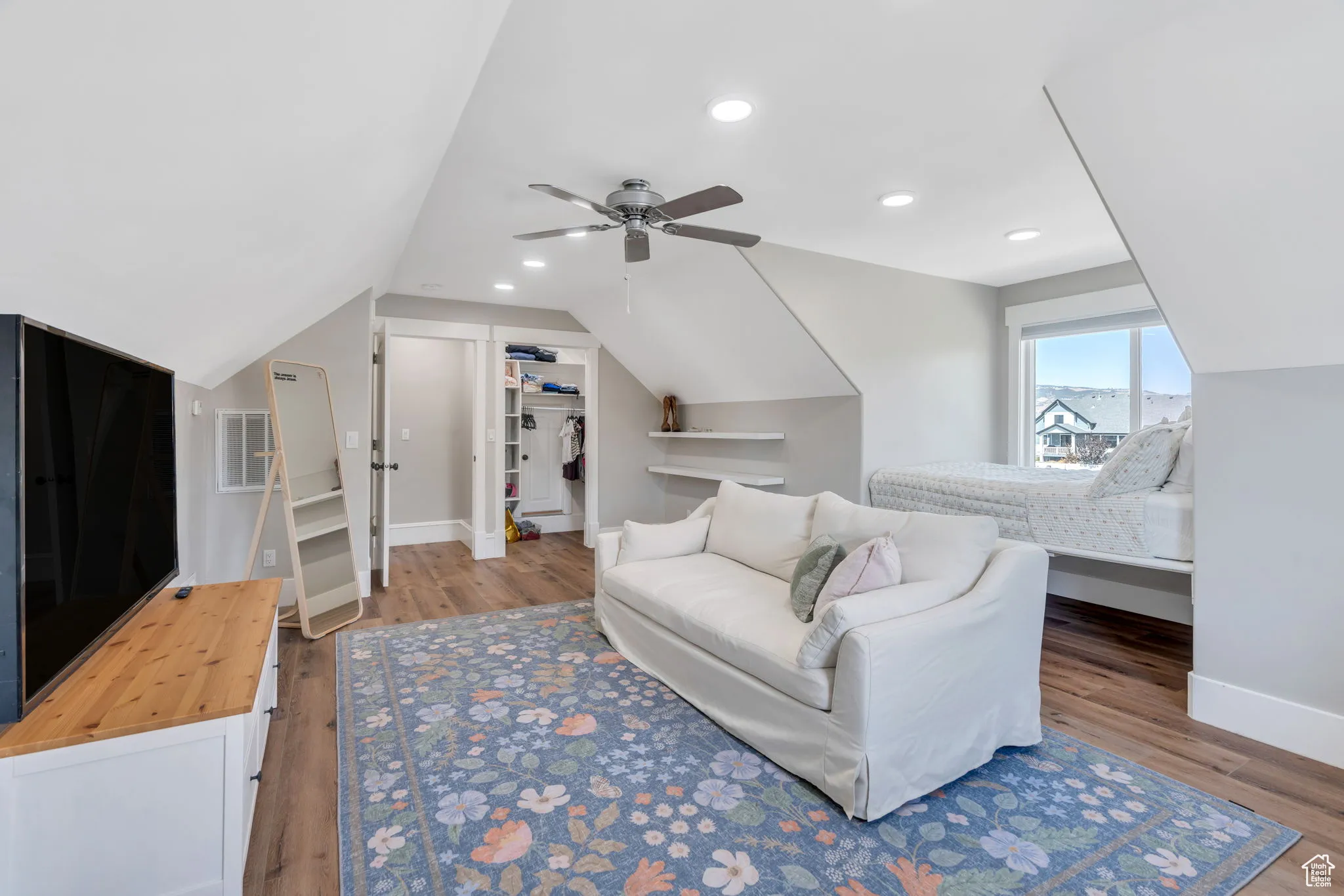 Bedroom with a walk in closet, lofted ceiling, recessed lighting, ceiling fan, and wood finished floors