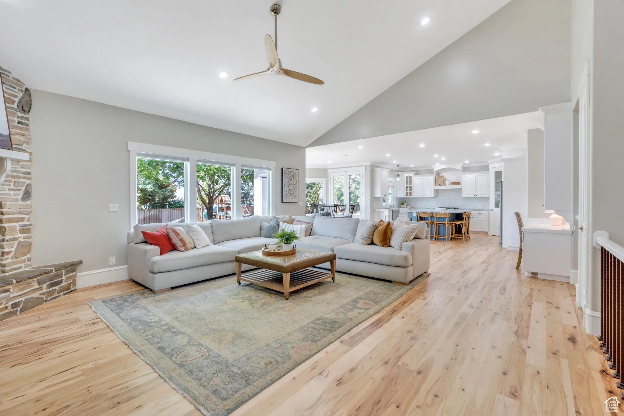 Living area with high vaulted ceiling, recessed lighting, light wood-style flooring, and ceiling fan