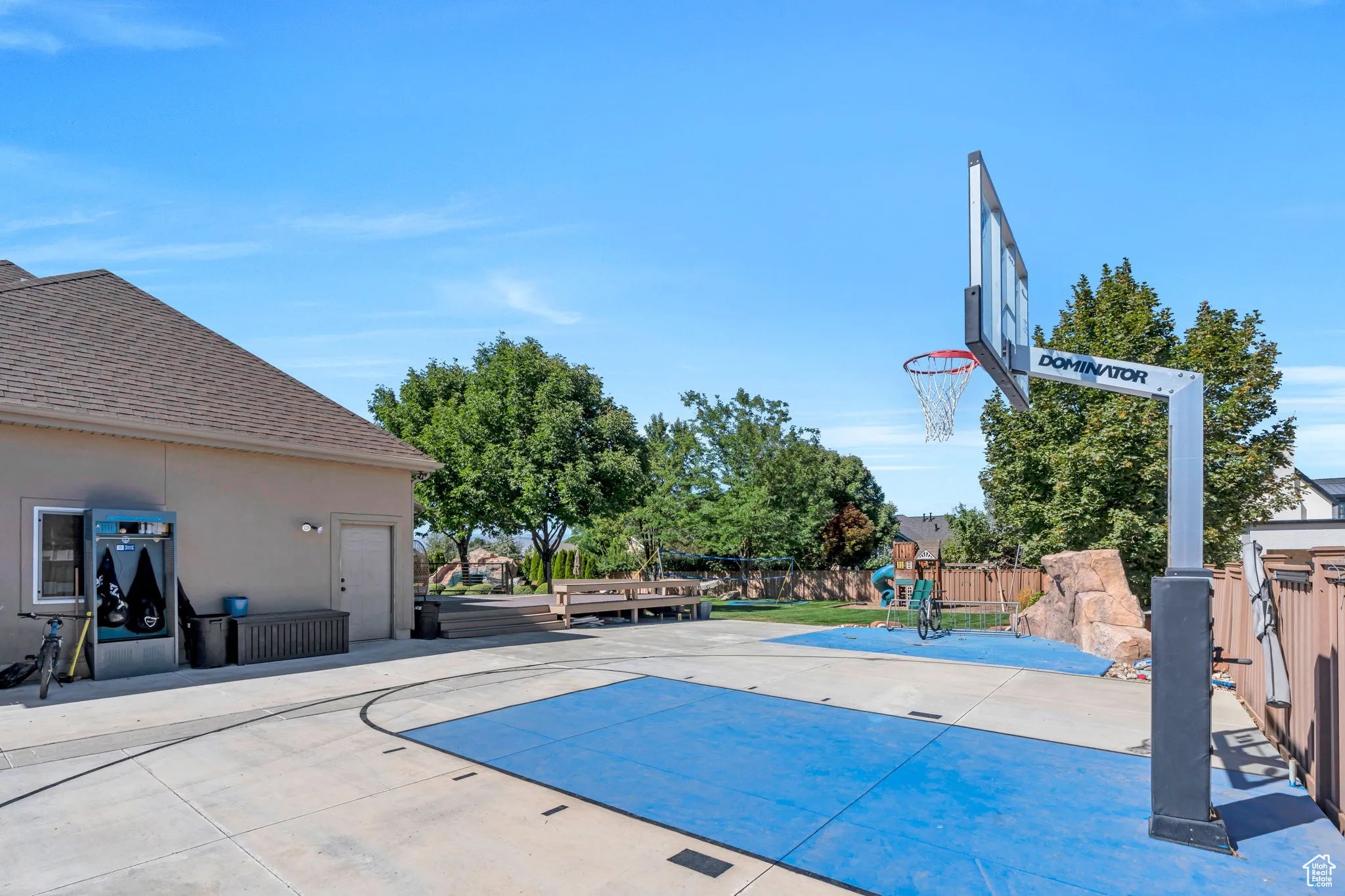 View of basketball court featuring a patio area, basketball hoop, and a playground