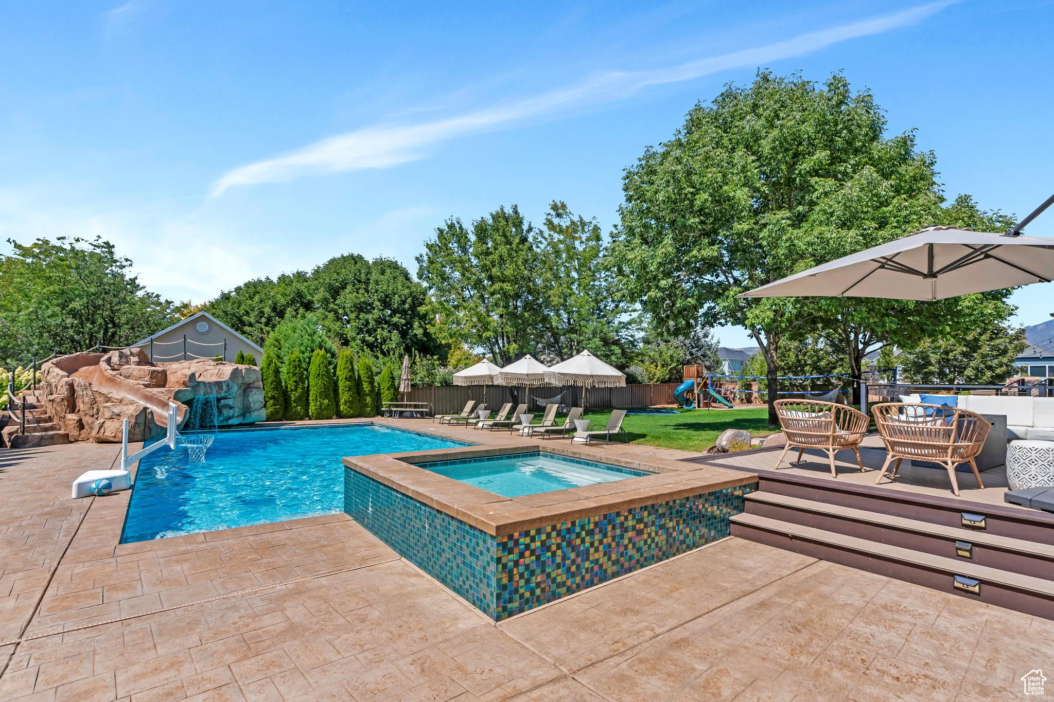 View of swimming pool with a water slide, a patio area, a fenced backyard, a deck, and a pool with connected hot tub