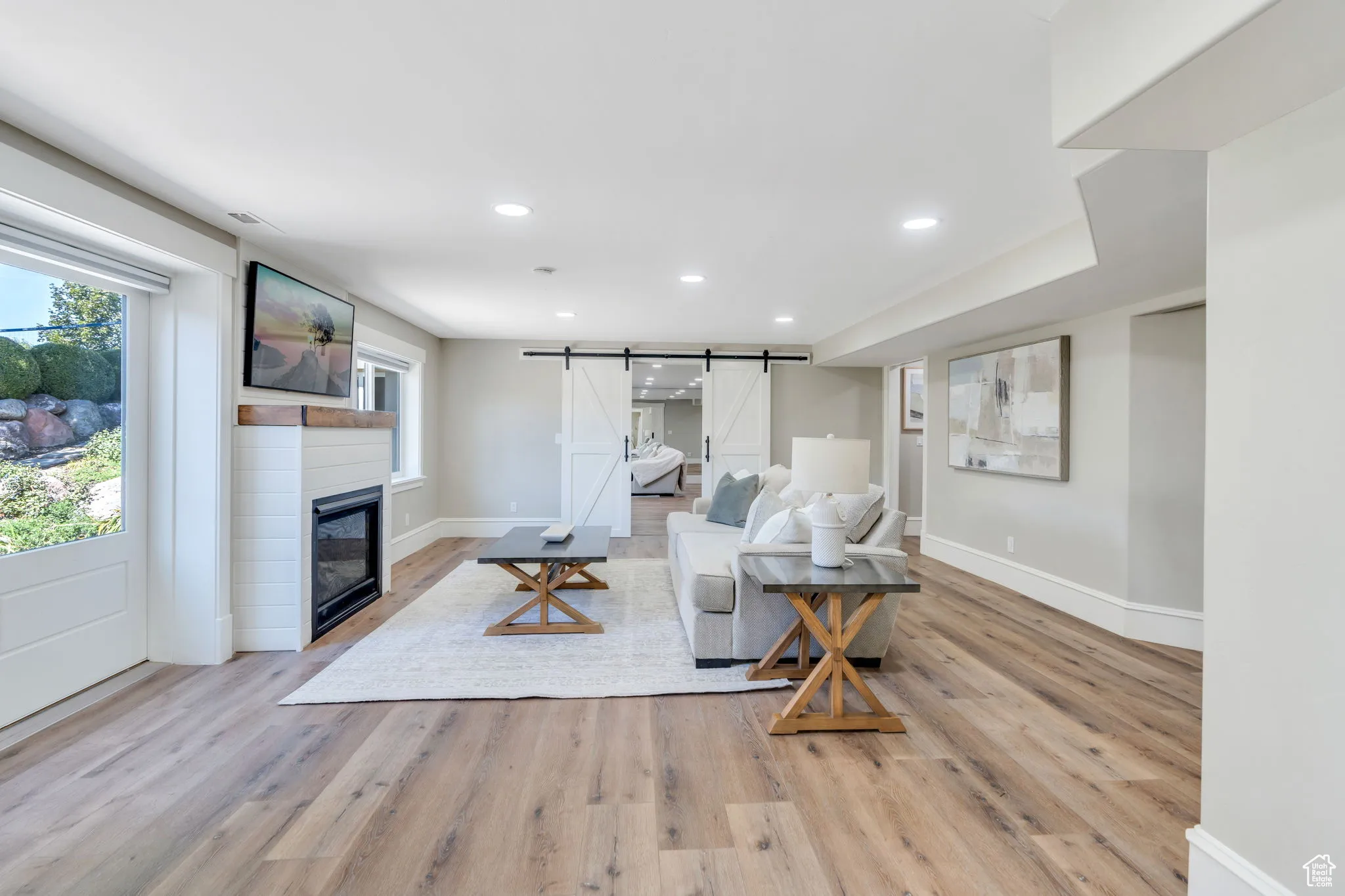 Living room featuring a barn door, recessed lighting, plenty of natural light, light wood-type flooring, and a large fireplace