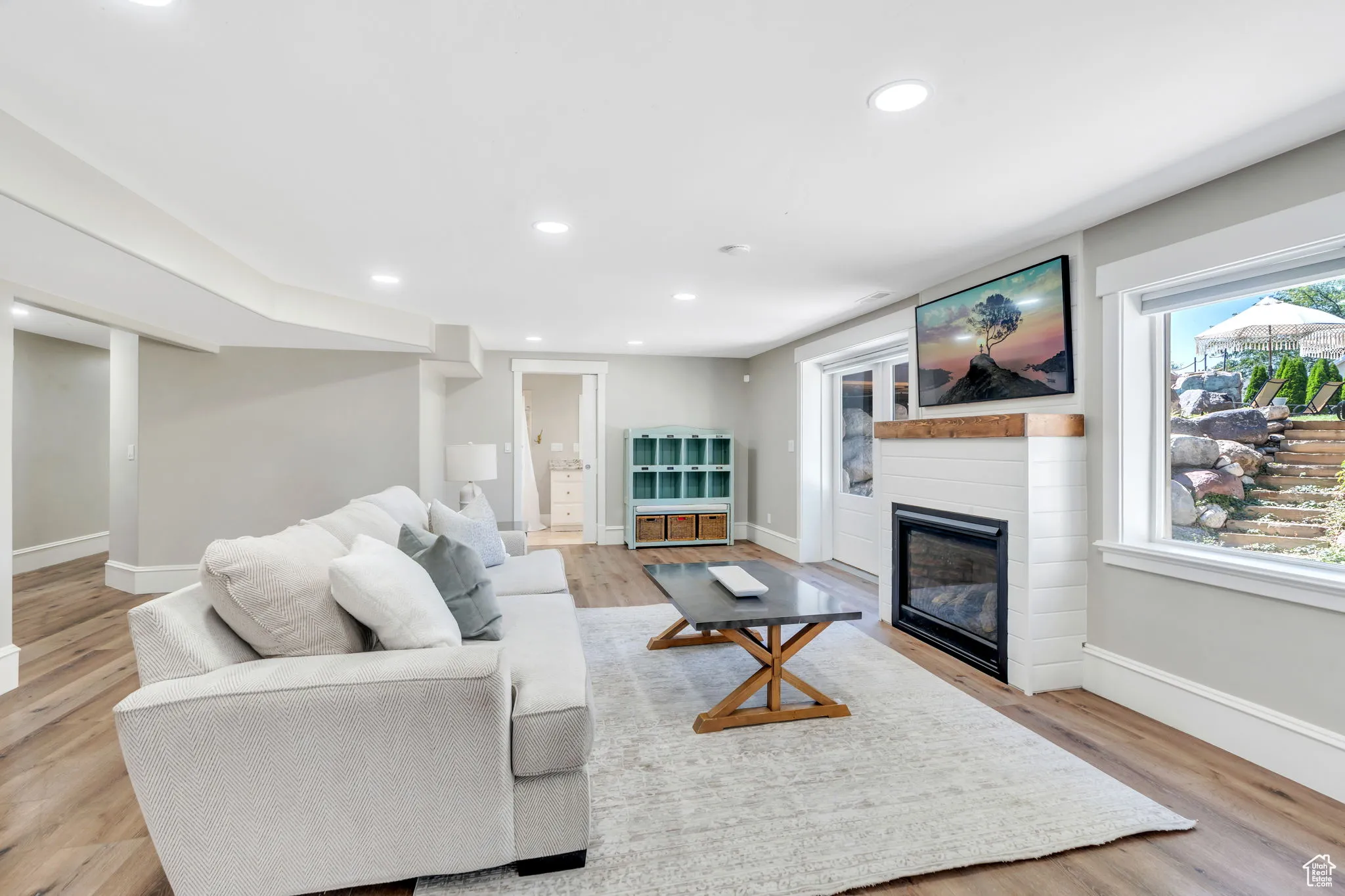 Living room featuring recessed lighting, a glass covered fireplace, and light wood-type flooring