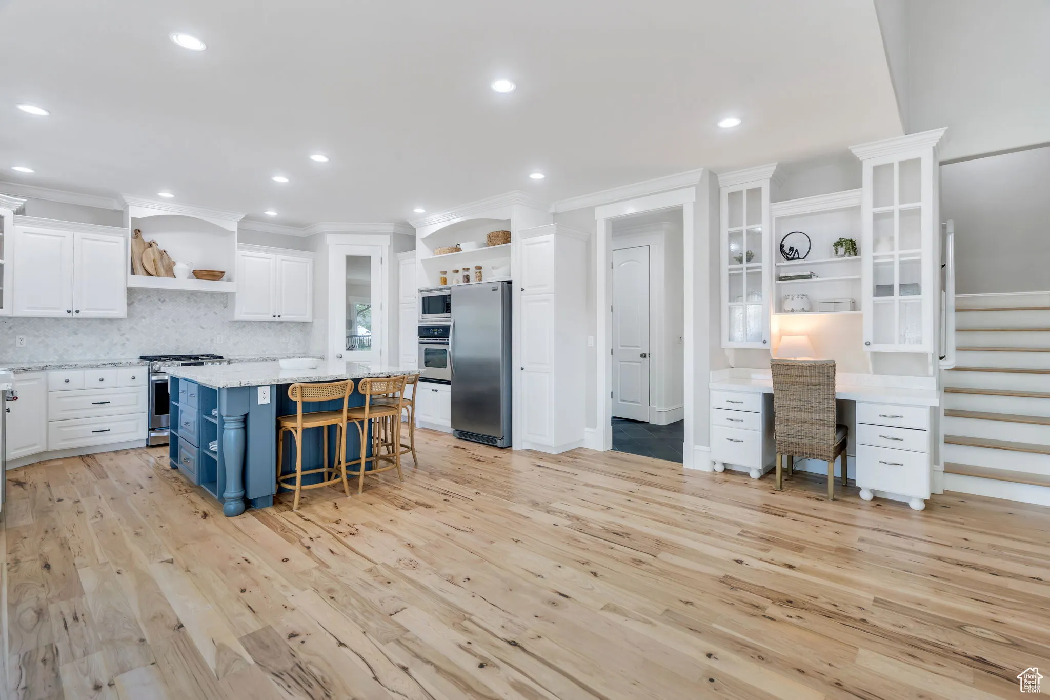 Kitchen featuring open shelves, blue cabinets, white cabinets, tasteful backsplash, and light stone countertops