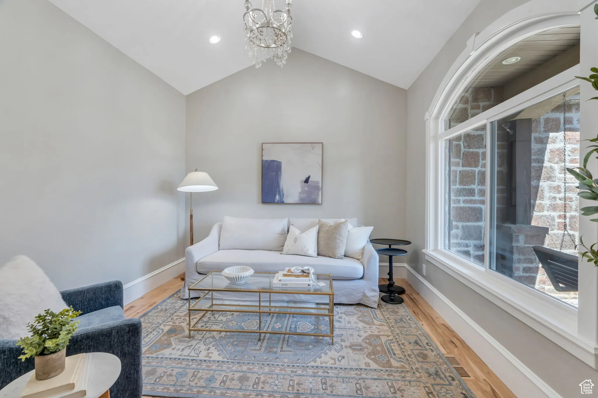 Living area featuring wood finished floors, vaulted ceiling, and a chandelier