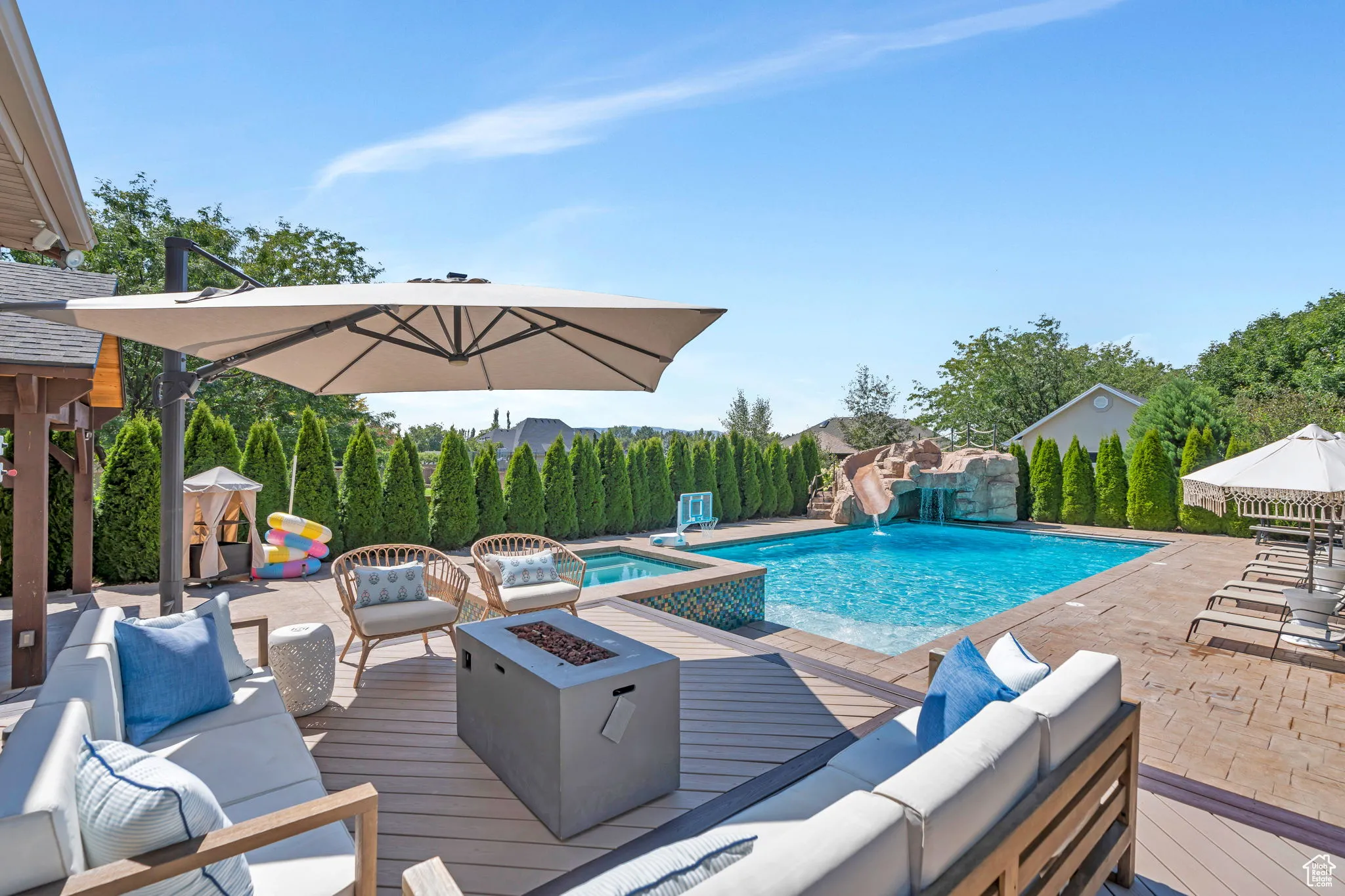 View of pool with an outdoor living space with a fire pit, a patio area, a deck, and a water slide
