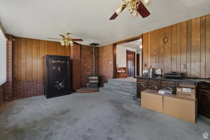 Living area featuring wooden walls, a wood stove, brick wall, and carpet floors