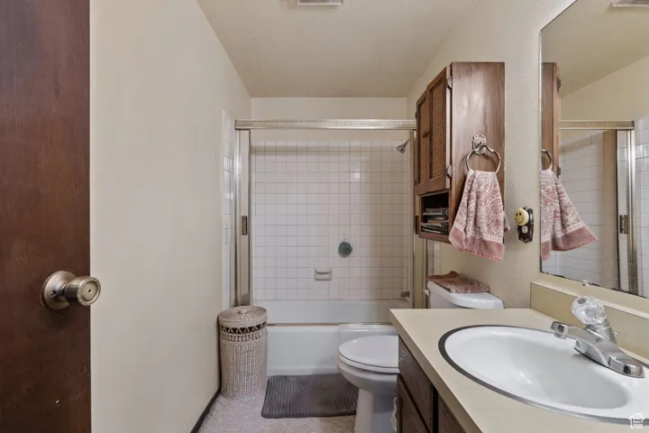Full bath with  shower combination, vanity, a textured wall, and a textured ceiling