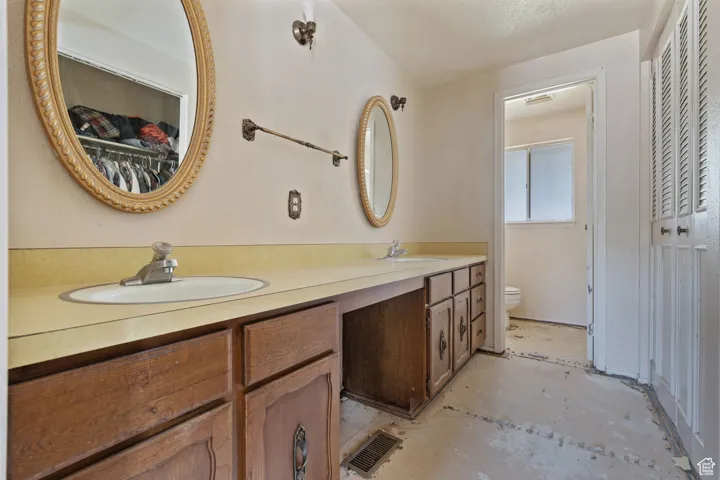 Full bathroom featuring double vanity, a closet, and concrete flooring