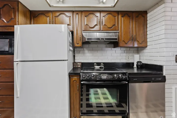 Kitchen featuring dark countertops, black appliances, tasteful backsplash, and brown cabinets