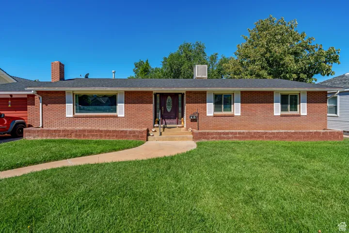 Ranch-style home with brick siding, a front lawn, a chimney, and roof with shingles
