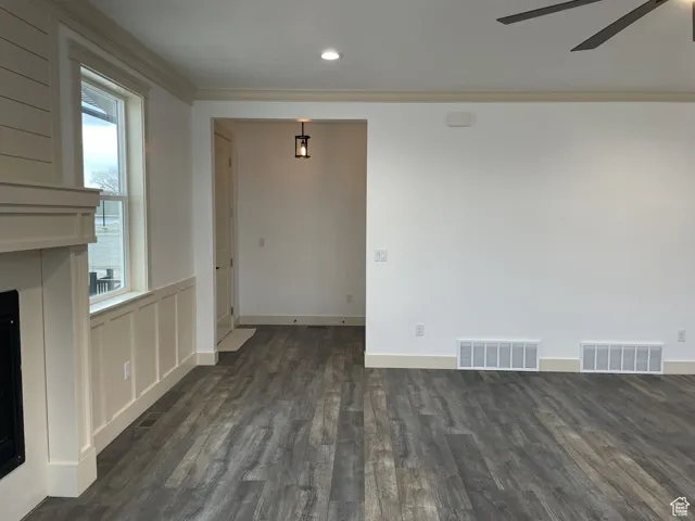 Unfurnished dining area with ornamental molding, dark wood-style floors, a fireplace, recessed lighting, and a ceiling fan