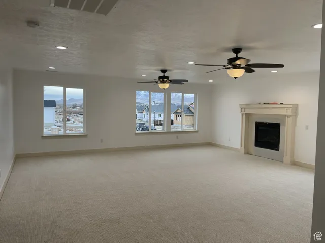 Unfurnished living room with light carpet, a fireplace, recessed lighting, and a textured ceiling
