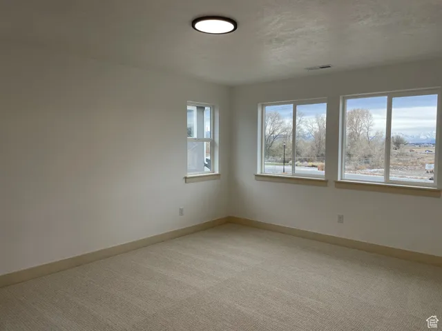 Spare room featuring baseboards and light colored carpet
