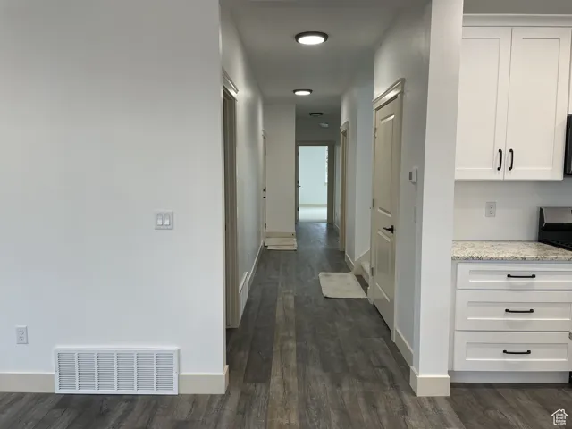 Hallway with baseboards and dark wood-type flooring