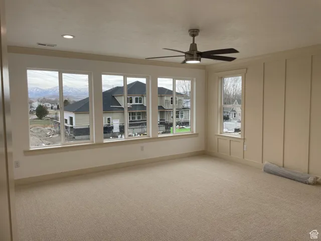 Unfurnished room featuring carpet, plenty of natural light, and ceiling fan