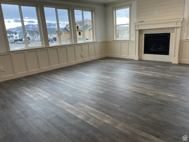 Unfurnished living room with a mountain view, a decorative wall, a fireplace, a residential view, and dark wood-style flooring