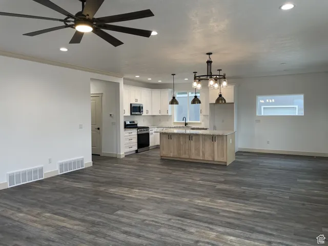 Kitchen featuring open floor plan, stainless steel appliances, hanging light fixtures, dark wood-style floors, and recessed lighting