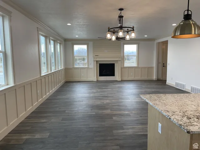 Unfurnished living room with ornamental molding, dark wood finished floors, a fireplace, a decorative wall, and recessed lighting