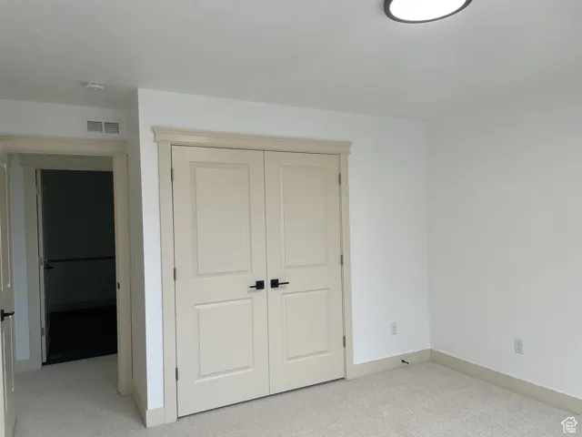 Unfurnished bedroom with light carpet and a closet