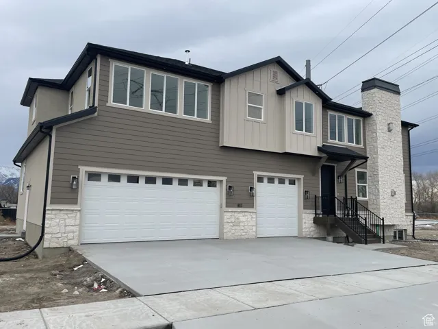 View of front of house with stone siding, a garage, and concrete driveway