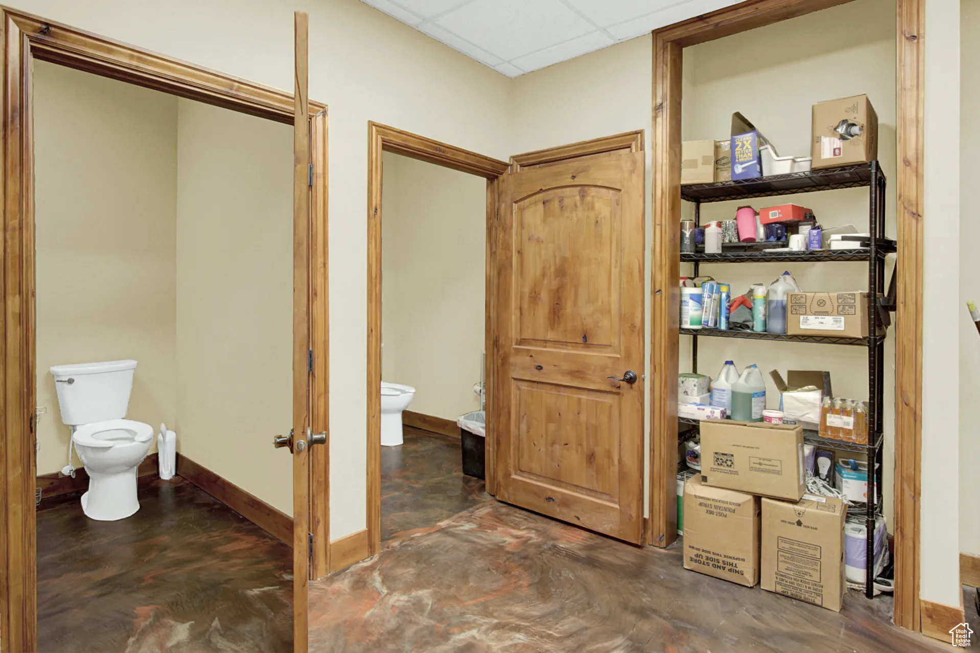 Bathroom with a paneled ceiling and concrete flooring