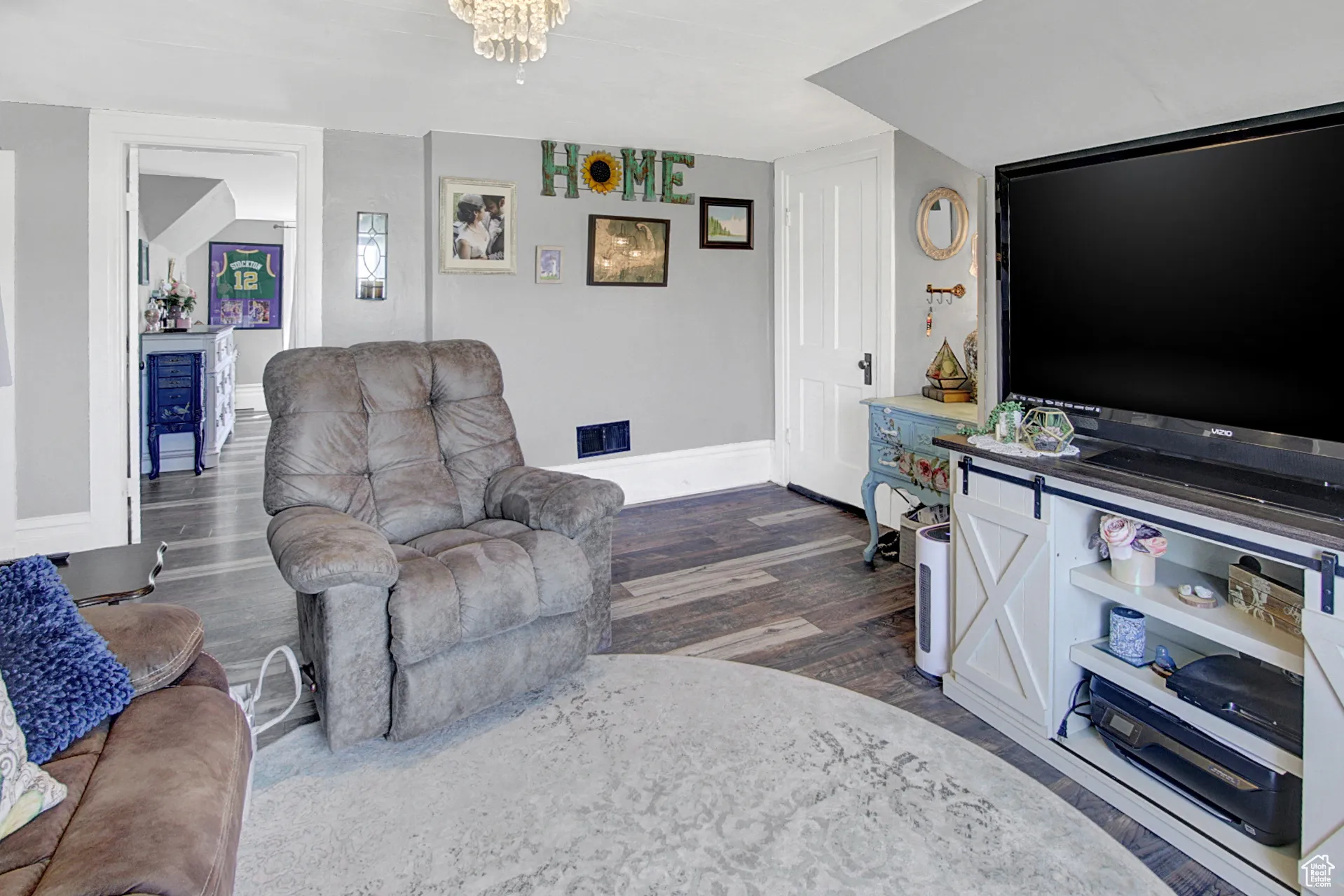 Living area featuring dark wood-style flooring and a chandelier