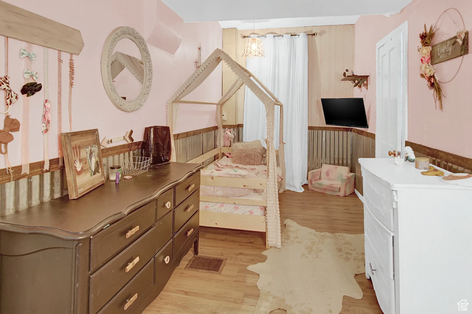 Bedroom featuring light wood-style floors, wood walls, and wainscoting