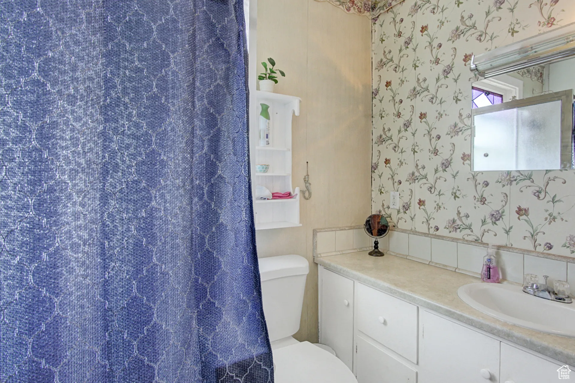 Full bath featuring wallpapered walls, vanity, and curtained shower