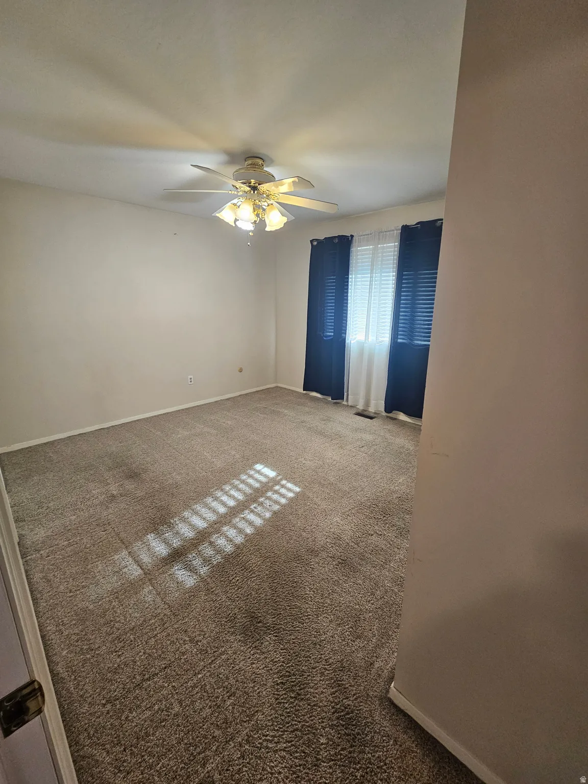 Unfurnished room with carpet flooring and a ceiling fan