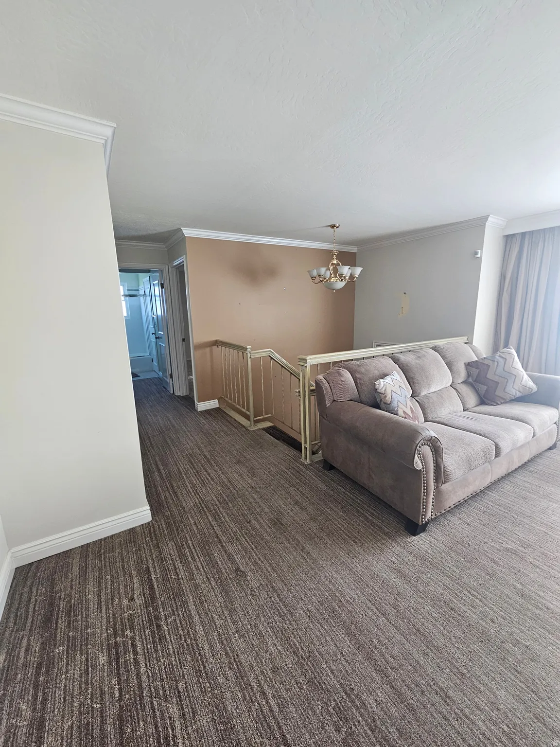 Living area with ornamental molding, a chandelier, dark carpet, and a textured ceiling