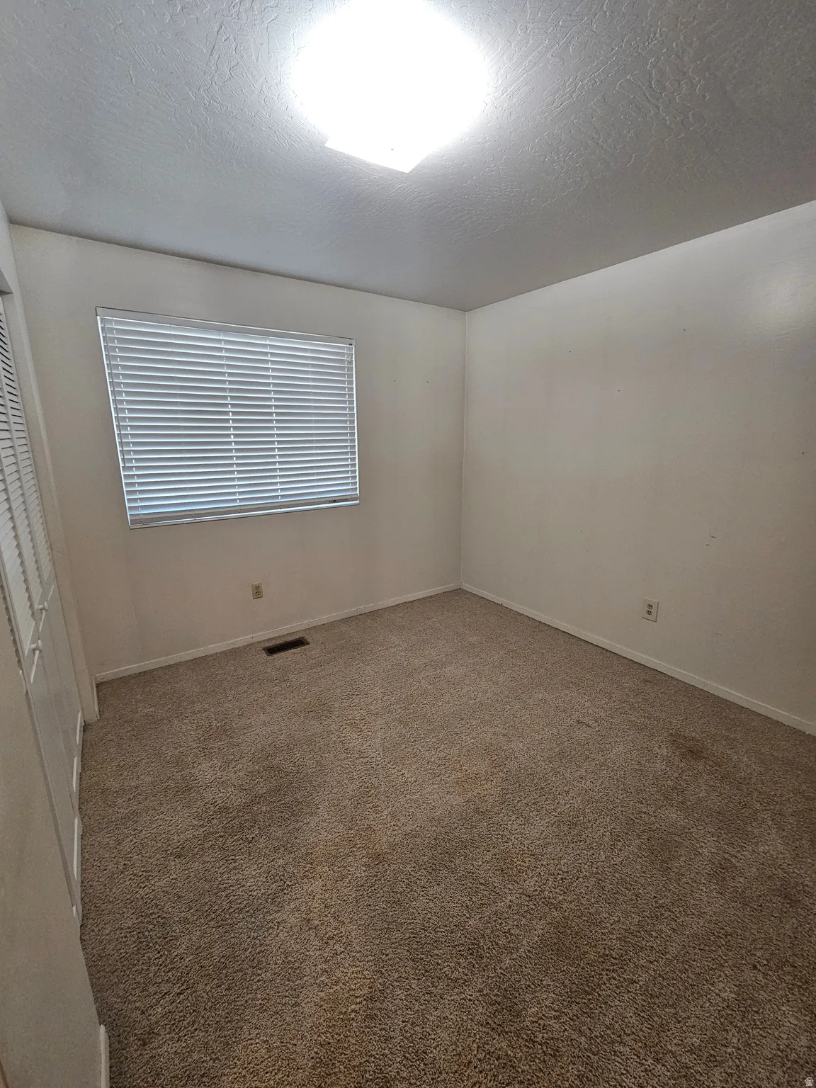 Carpeted spare room with a textured ceiling