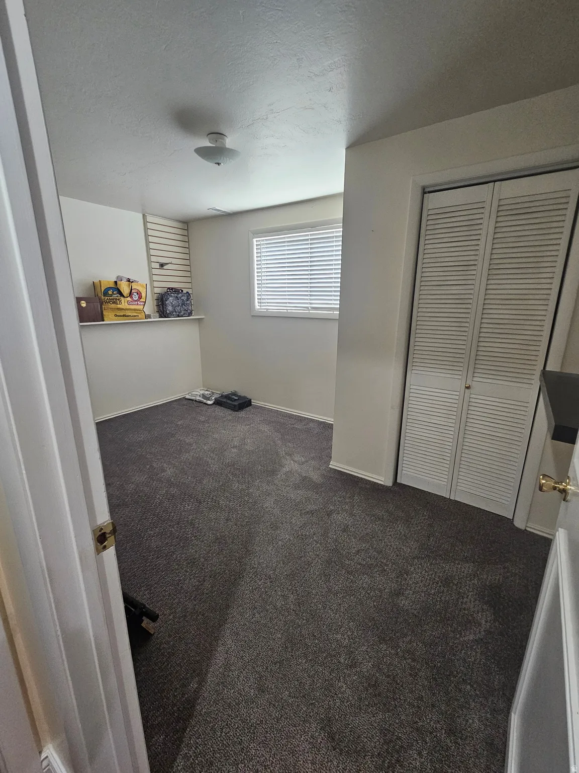 Bedroom with a textured ceiling, dark colored carpet, and a closet