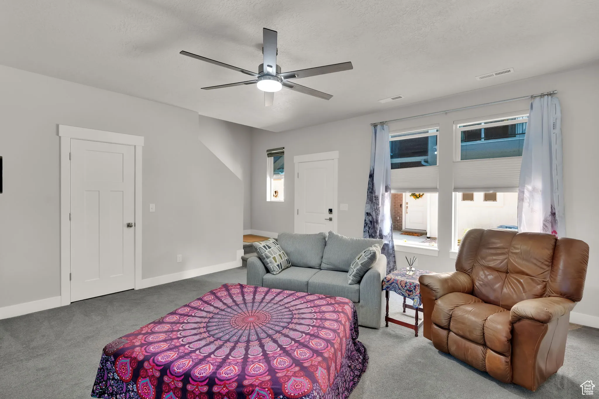 Great room with plenty of natural light, carpet floors and large upgraded ceiling fan