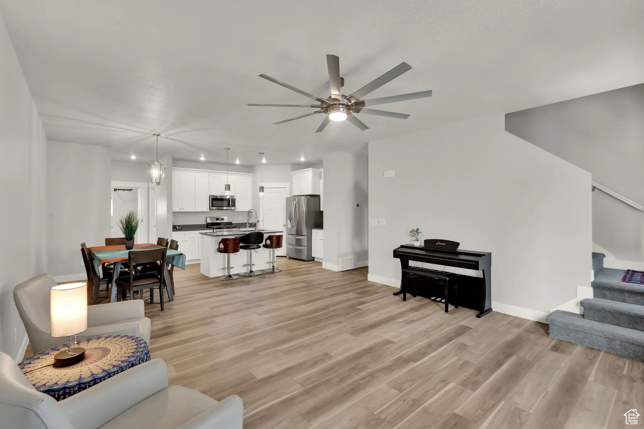 Living area featuring stairway, light wood-style LVP floors, and an upgraded ceiling fan