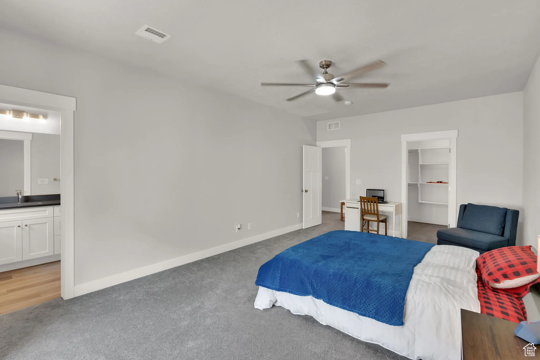 Primary bedroom with a walk in closet, light colored carpet, an upgraded remote controlled ceiling fan, and ensuite bath with LARGE upgraded walk in shower.