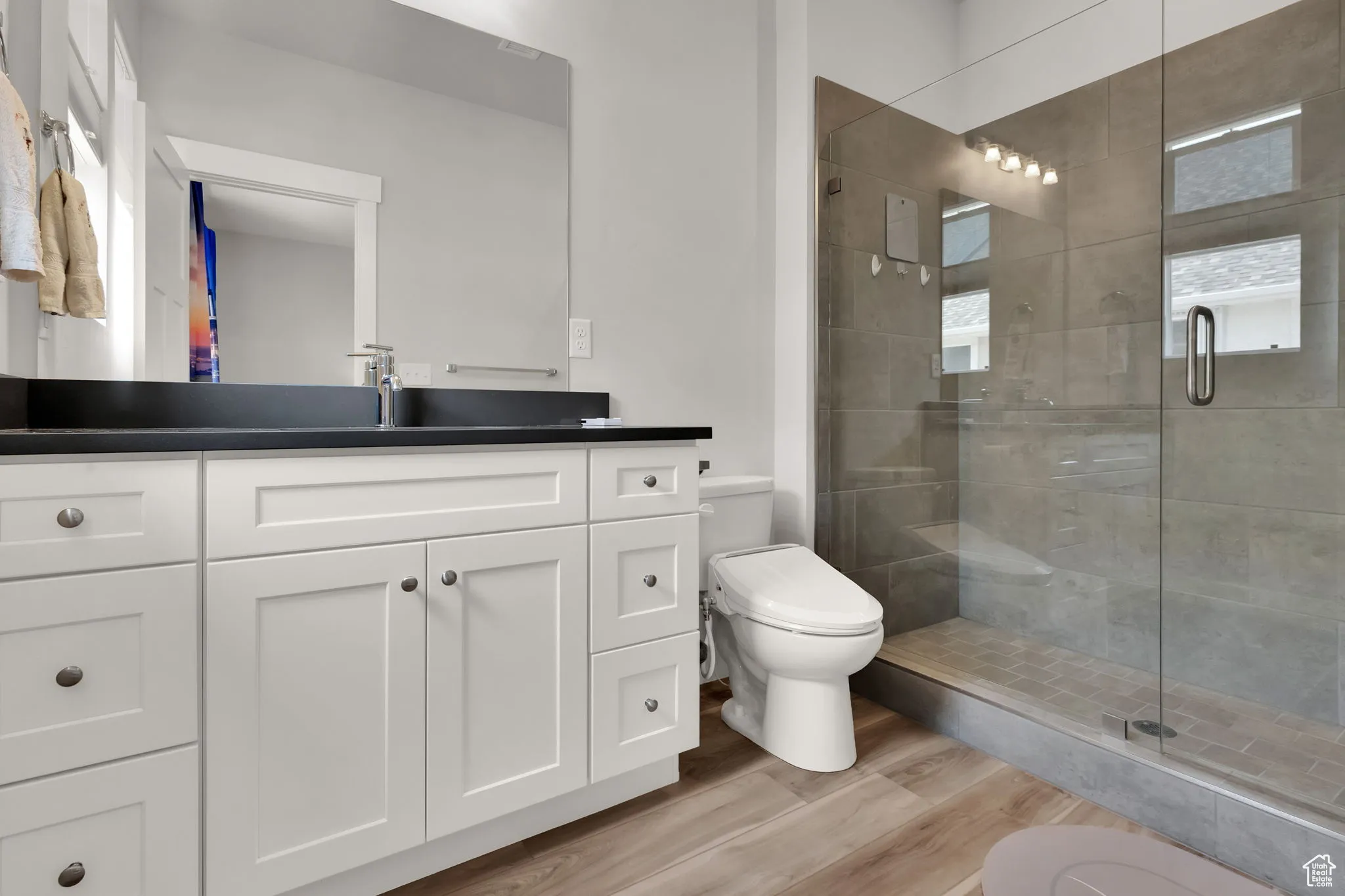 Primary bath featuring vanity, an upgraded stall walk in shower, and light wood-style LVP flooring