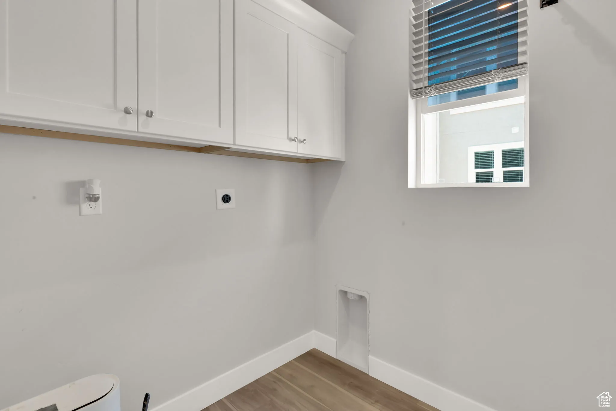 Laundry room with hookup for an electric dryer, cabinet space, light wood-style LVP flooring & window for natural lighting!